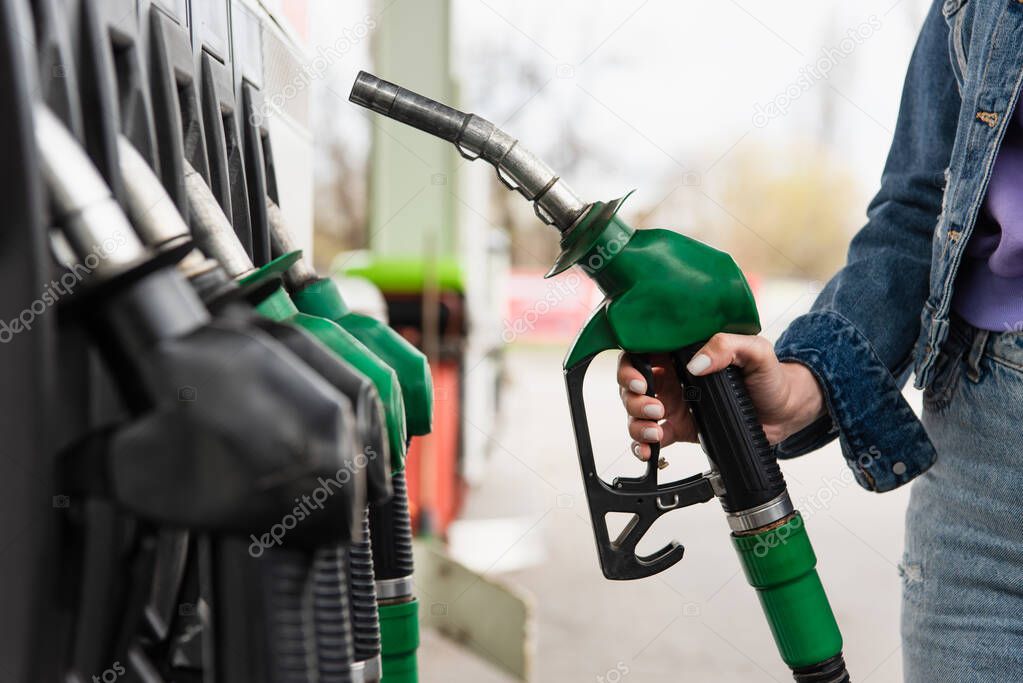 cropped view of woman holding petrol pistol on gas station