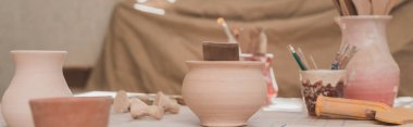 handmade clay pots with pottery equipment on wooden table, banner