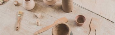 high angle view of handmade clay pots with spatulas on wooden table in pottery, banner