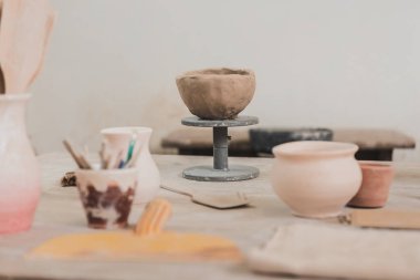 sculpted clay bowl on wooden table in pottery art studio