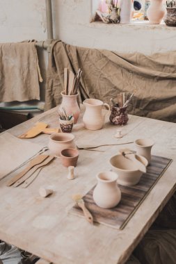 high angle view of handmade clay pots near equipment on wooden table in pottery