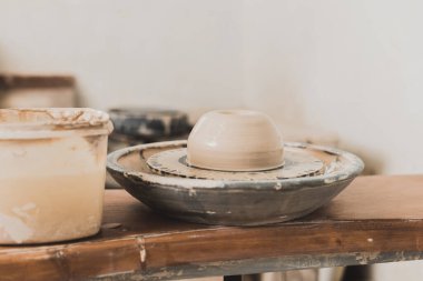 pottery wheel with wet clay piece on wooden bench in art studio