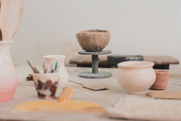 sculpted clay bowl on wooden table in pottery art studio