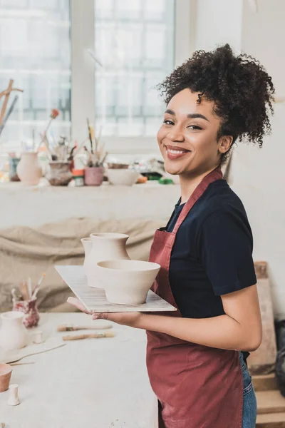 Sonriente Joven Afroamericana Mujer Sosteniendo Ollas Barro Bandeja Cerámica — Foto de Stock