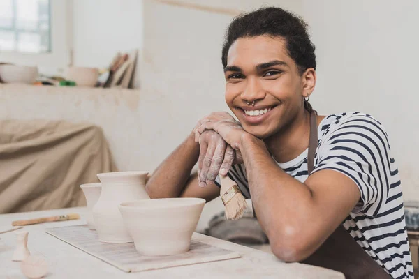 Sonriente Joven Afroamericano Hombre Sentado Cerca Ollas Barro Con Las —  Fotos de Stock