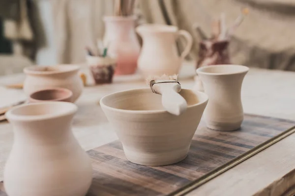 陶器中的木制桌子上有刷子的手工黏土碗 — 图库照片