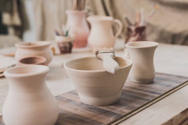 handmade clay bowls with brush on wooden table in pottery