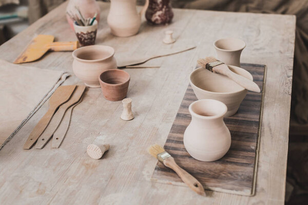 high angle view of handmade clay pots on wooden table near equipment in pottery