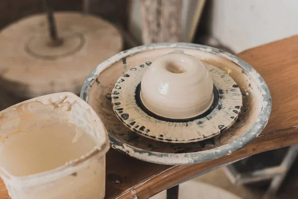 pottery wheel with wet clay on wooden bench in art studio