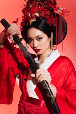 Young asian woman holding sheath and sword on red background  clipart