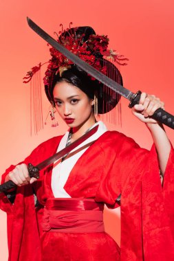 Geleneksel kimonolu Japon kadın ve kırmızı arka planda kılıç tutan saç modeli. 