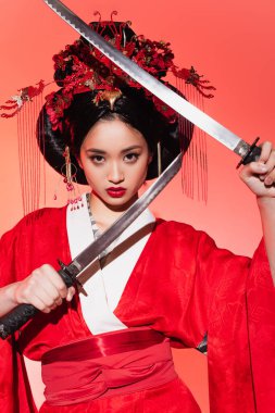 Kırmızı arka planda kılıç tutan Asyalı güzel bir kadın. 
