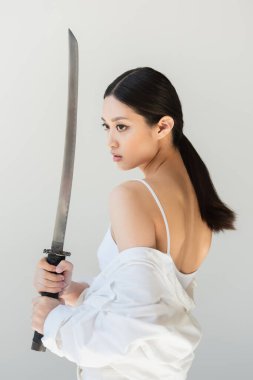 Wakizashi 'nin kılıcını gri üzerinde tutan güzel Japon kadın.