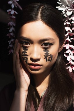 Siyah yüzlü, saç çizgileri ve hiyeroglifleri olan genç Japon kadın. 