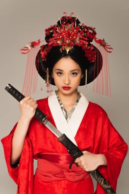 Asian woman in national clothes holding weapon isolated on grey  clipart