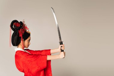 Kılıçlı Japon kadının gri üzerinde tek başına duruşu. 