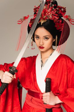 Kırmızı kostümlü güzel bir Asyalı kadın. Elinde gri bir kılıç var. 