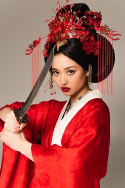 Ulusal saç stili olan Japon kadın gri üzerinde kılıç tutuyor. 