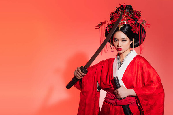 Asian woman with sword looking at camera on red background 