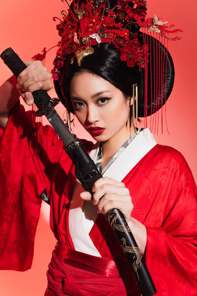 Young asian woman holding sheath and sword on red background 