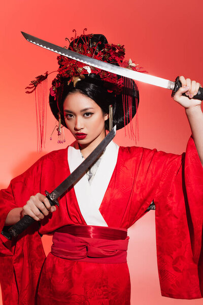 Japanese woman in red kimono holding swords on red background 