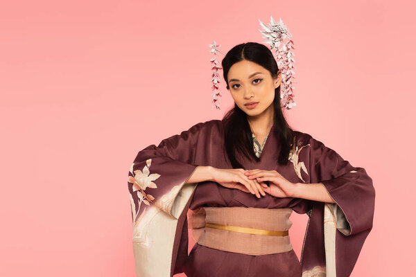 Young asian woman with traditional hairdo posing isolated on pink 
