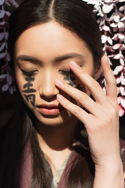 用象形文字触摸脸的日本女人被隔离在黑暗中 — 图库照片