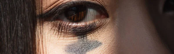 Close up view of eye of asian woman with paint on face, banner