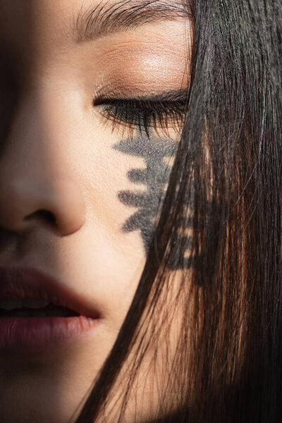Close up view of japanese woman with hieroglyphs and closed eye