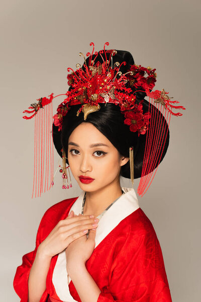 Young japanese woman in red costume looking at camera isolated on grey 