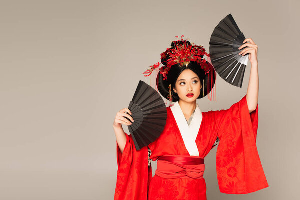Japanese woman in oriental clothes holding fans isolated on grey 