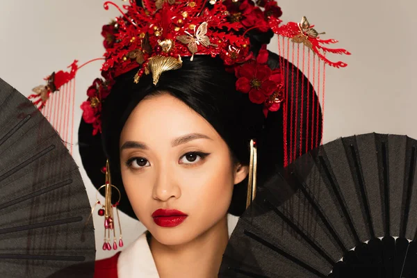 Black fans near japanese woman with traditional hairstyle isolated on grey