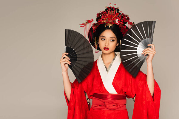 Японская женщина в кимоно позирует с вентиляторами, изолированными на сером 