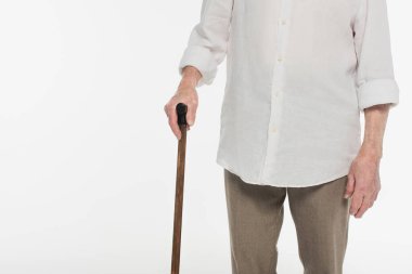 Yaşlı bir adamın günlük kıyafetleri içinde yürüme sopası tutarken görüntüsü beyaz üzerine izole edilmiş.