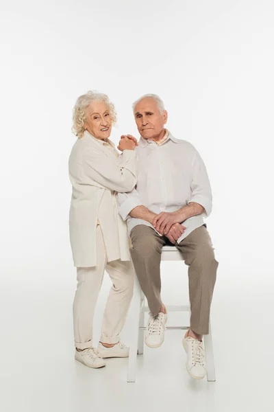 Smiling Elderly Woman Hugging Husband Sitting Stool White — Stock Photo, Image