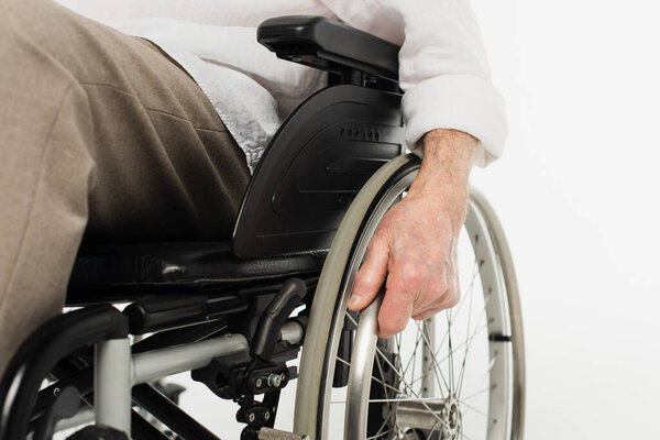 partial view of elderly man sitting in wheelchair isolated on white