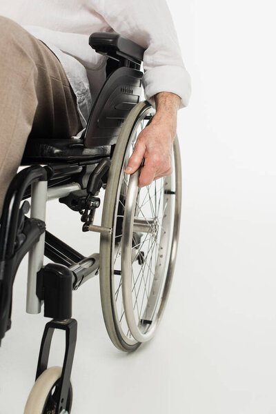 partial view of elderly man sitting in wheelchair on white