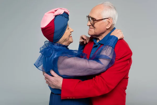 Smiling Elderly Couple Blue Dress Red Blazer Hugging Isolated Grey — Stock Photo, Image