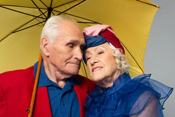 Anciano Con Paraguas Amarillo Abrazando Esposa Vestido Azul Turbante Aislado — Foto de Stock