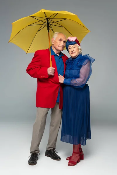 Elderly Man Red Blazer Yellow Umbrella Hugging Wife Blue Dress — Stock Photo, Image