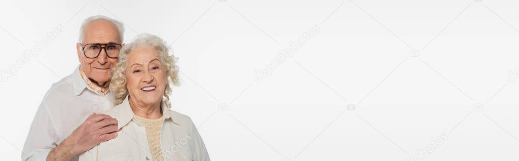 elderly man in casual clothes hugging wife and looking at camera isolated on white, banner