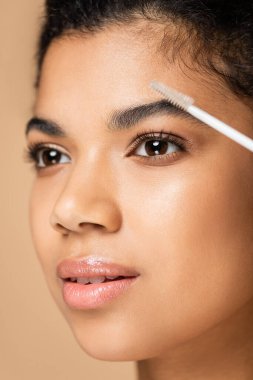 Bej rengi kaşları olan, çıplak omuzlu, Afro-Amerikalı bir kadına yakın durun. 