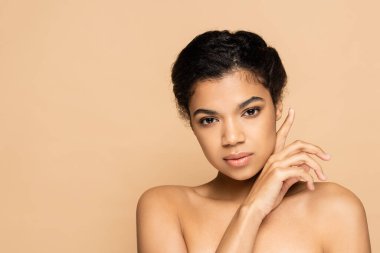 Bej rengi üzerinde çıplak omuzlu Afrikalı Amerikalı genç bir kadın. 