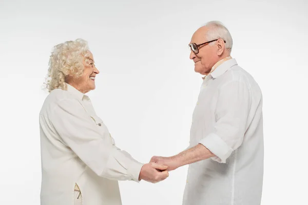 白い服を着て手を取り合い孤立した老夫婦の笑顔を — ストック写真