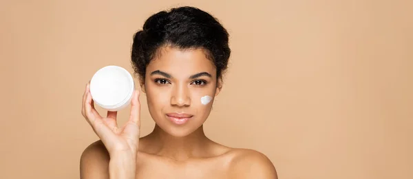 Morena Mujer Afroamericana Con Crema Facial Las Mejillas Sosteniendo Contenedor — Foto de Stock