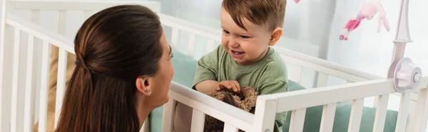 Uśmiechnięte Dziecko Miękką Zabawką Patrzące Matkę Sypialni Baner — Zdjęcie stockowe