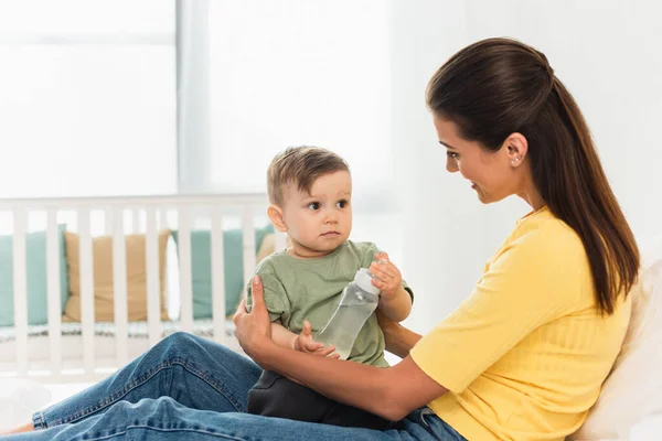 Lächelnde Mutter Umarmt Sohn Mit Babyflasche Bett — Stockfoto