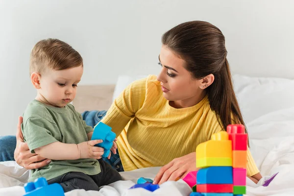 Giovane Madre Abbracciando Bambino Con Blocchi Costruzione Camera Letto — Foto Stock