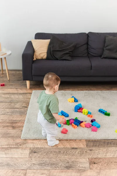 家でカラフルな建物ブロックの近くに立っている幼児の男の子の高い角度ビュー — ストック写真