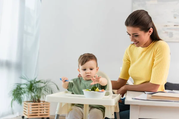 Donna Felice Guardando Figlio Seduto Vicino Ciotola Verdure Sul Seggiolone — Foto Stock